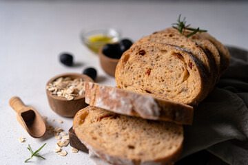 Homemade sourdough ciabatta slice bread with olives and rosemary on a white abstract table. Artisan bread