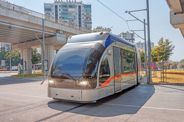 Modern comfortable tram moves along turn the streets under bridge junction of the city, electric transport.