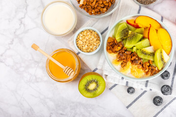 Bowl of granola with yogurt and fresh berries on a texture table. Yogurt berries, acai bowl, spirulina bowl. Healthy food, balanced breakfast. Strawberries, blueberries, kiwi, peach, almonds and chia.