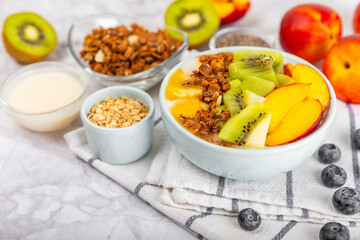 Bowl of granola with yogurt and fresh berries on a texture table. Yogurt berries, acai bowl, spirulina bowl. Healthy food, balanced breakfast. Strawberries, blueberries, kiwi, peach, almonds and chia.