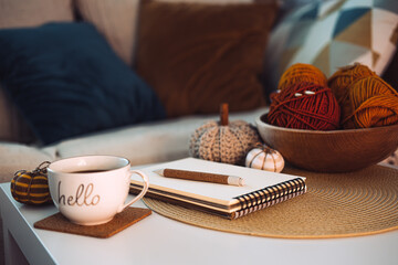 Start new autumn day with coffee cup with text hello and cozy fall decorations on table. Start of...