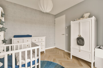 Crib and wardrobe in white baby room at home