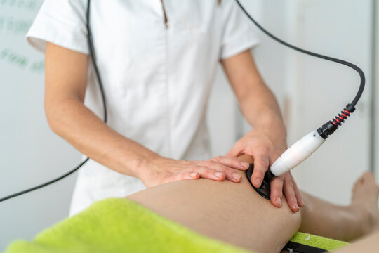 Crop therapist doing shock wave therapy to patient