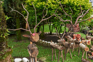 Family of handmade Christmas reindeer made of wooden logs placed outdoors in a garden.