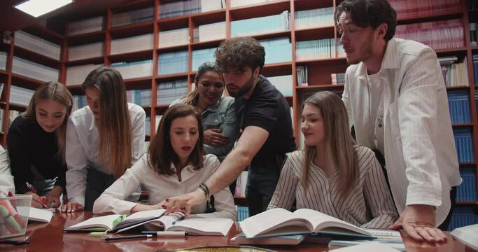 Group of diverse students consulting with the professors in the university library setting