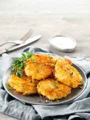 Close up view of potato pancakes. Potatoes pancakes latkes, flapjacks, hash brown or potato vada on gray plate over gray wooden table, with fresh parsley and sour cream. Copy space for text.