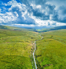 Beautiful road along green mountains with sheep roaming around in Dent, Deepdale, Yorkshire Dales, England, United Kingdom