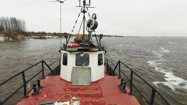 View from the industrial boat with a barge sailing behind. Clip. Concept of water transportation of goods.