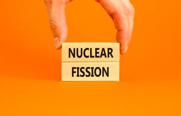 Nuclear fission symbol. Concept words Nuclear fission on beautiful wooden blocks. Beautiful orange table orange background. Businessman hand. Business science nuclear fission concept. Copy space.