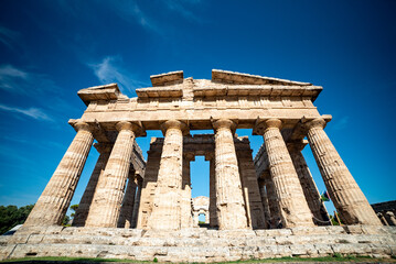 Ancient greek temples located in Italy in Peastum, Salerno with columns and blue sky and sun...