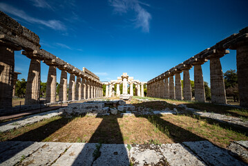 Ancient greek temples located in Italy in Peastum, Salerno with columns and blue sky and sun...