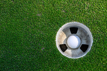 Closeup of white golf ball in the cup on a putting green
