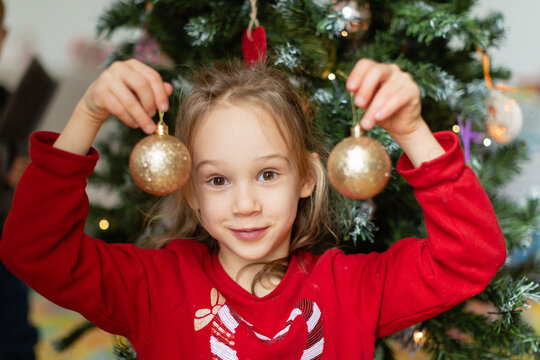 Girl with bauble against Christmas tree