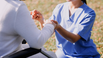 Asian young woman nurse at nursing home take care disabled senior man. Caregiver doctor serve...