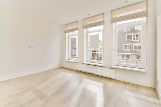 Empty living room with large windows and white walls