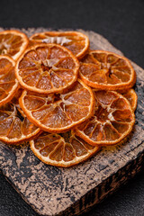 Dried round slices of tangerine, orange or lemon on a dark concrete background