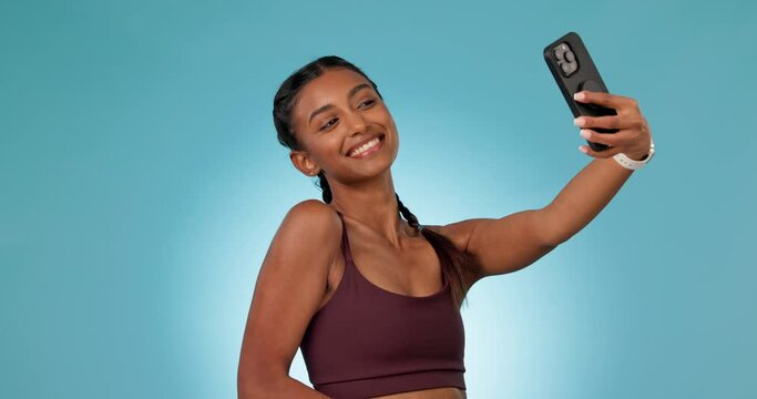 Woman, fitness selfie and studio with peace sign, pout lips or photography for smile by blue background. Influencer girl, emoji or icon with kiss, profile picture or post on web, social media or app