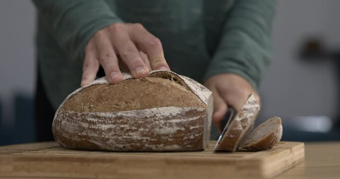 Close-up hand cutting slice of bread with knife in speed ramp slow-motion 800 fps