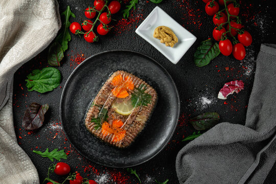 Meat aspic in a dark plate with mustard. Black background. Restaurant dishes