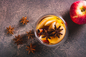 Close up of hot tea with apples, cinnamon, star anise and honey in a cup on the table top view