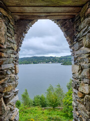 A stone built window which looks out into a lake