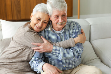 Senior adult mature couple hugging at home. Mid age old husband and wife embracing with tenderness love enjoying sweet bonding wellbeing. Grandmother grandfather together. Family moment love and care