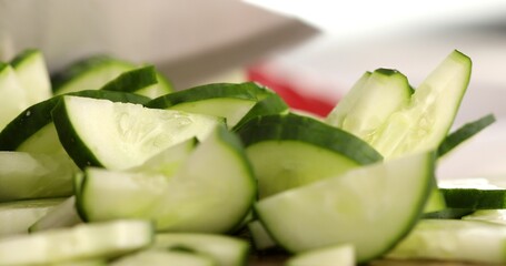 Fresh cucumber is cut into small slices. Close-up. Preparing vegetable salad. Healthly food.