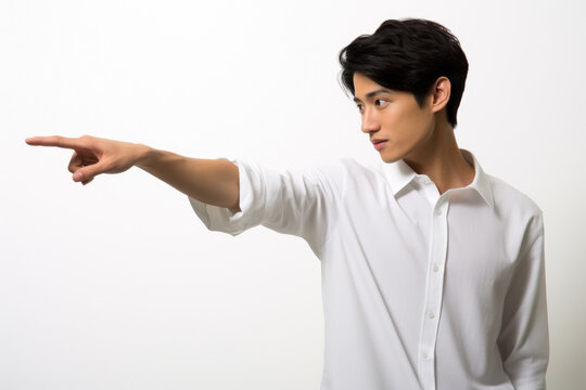 Man wearing white shirt is pointing at something. This image can be used to represent directions, instructions, or highlighting specific object or concept.