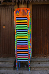 piled colorful plastic chairs in front of a wooden door