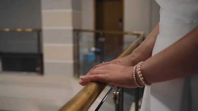 The girl gently puts her hands on the golden railing. The camera takes a close-up of the hands