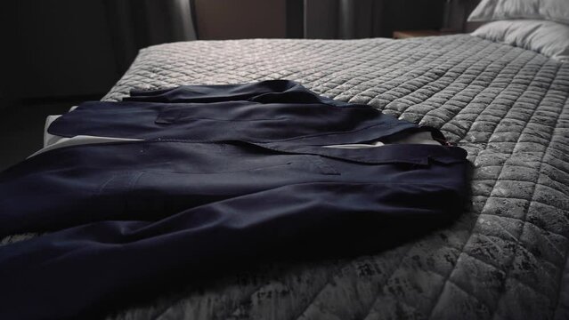 The man throws his jacket on the bed in slow motion. Close-up of a jacket falling on the bed