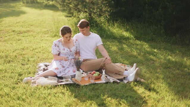 A guy and a girl are sitting on a blanket in the evening looking at old photos. Shooting in the evening on a sunny day