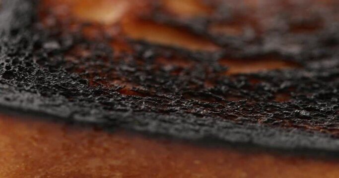 burnt toast. over toasted piece of bread. coal black surface of meal. macro dolly shot.