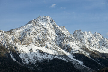 View of snow peaked mountains from Valle di Cadore  town. Blue sky in a sunny winter day; Dolomites, Italian alps, Italy