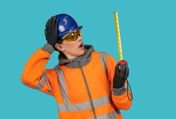 builder young woman in shock and wonder about size on blue background