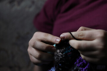 Skillful fingers of a young lady holding crochet hook and wool thread. Girls hands crocheting...