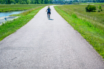 Fototapeta premium focus on near pavement with blurred distant child wearing a helmet while riding a bike on a park path 