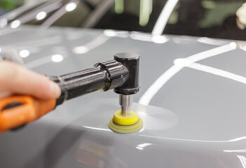 Car detailing series: Polishing gray car close-up. The process of polishing the car body in close-up. Selective focus.