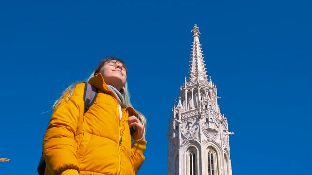 Holiday time by matthias church. A view of young modern girl admire the white Matthias church in Budapest during holiday time.