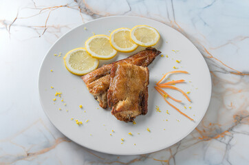 roasted pork ribs served on a white plate and resting on a marble table