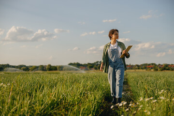 Female agronomist walks across an field during harvesting. Agricultural occupation concept