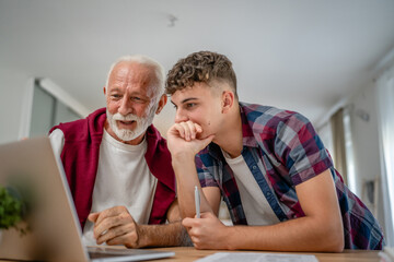 student caucasian male teenager and his grandfather or professor study