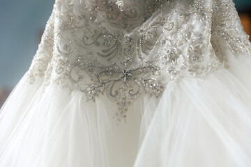 The bride's wedding dress is embellished with glittering patterns at the waist. The classic traditional white dress of the bride on the day of the ceremony. Bride's dress photographed close up