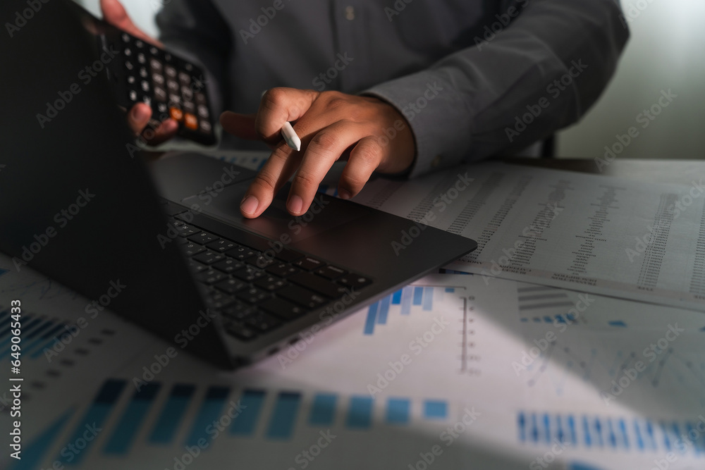 Poster close-up of a businessman using a computer laptop to analyze finances and calculate investment data 