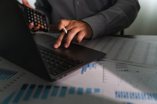 close-up of a businessman using a computer laptop to analyze finances and calculate investment data paperwork money report tax refund cost Accounting and Banking Concept