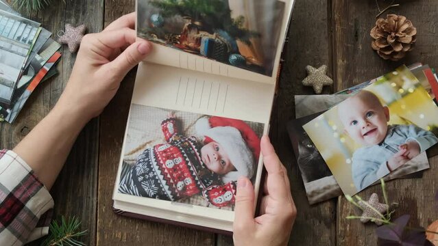 Christmas photo printing. Person looks through Christmas printed photos in family picture album.