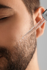 Man applying cosmetic serum onto face, closeup