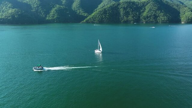 Drone footage of motorboat and sailboat on lake
