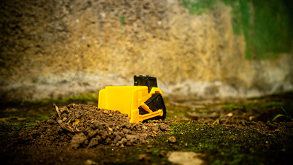 South Minahasa, Indonesia - January 3, 2023: a yellow bulldozer toy is leveling the ground