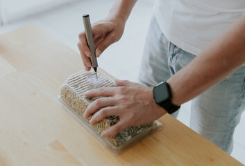 A young man drills a box with a mini drill.